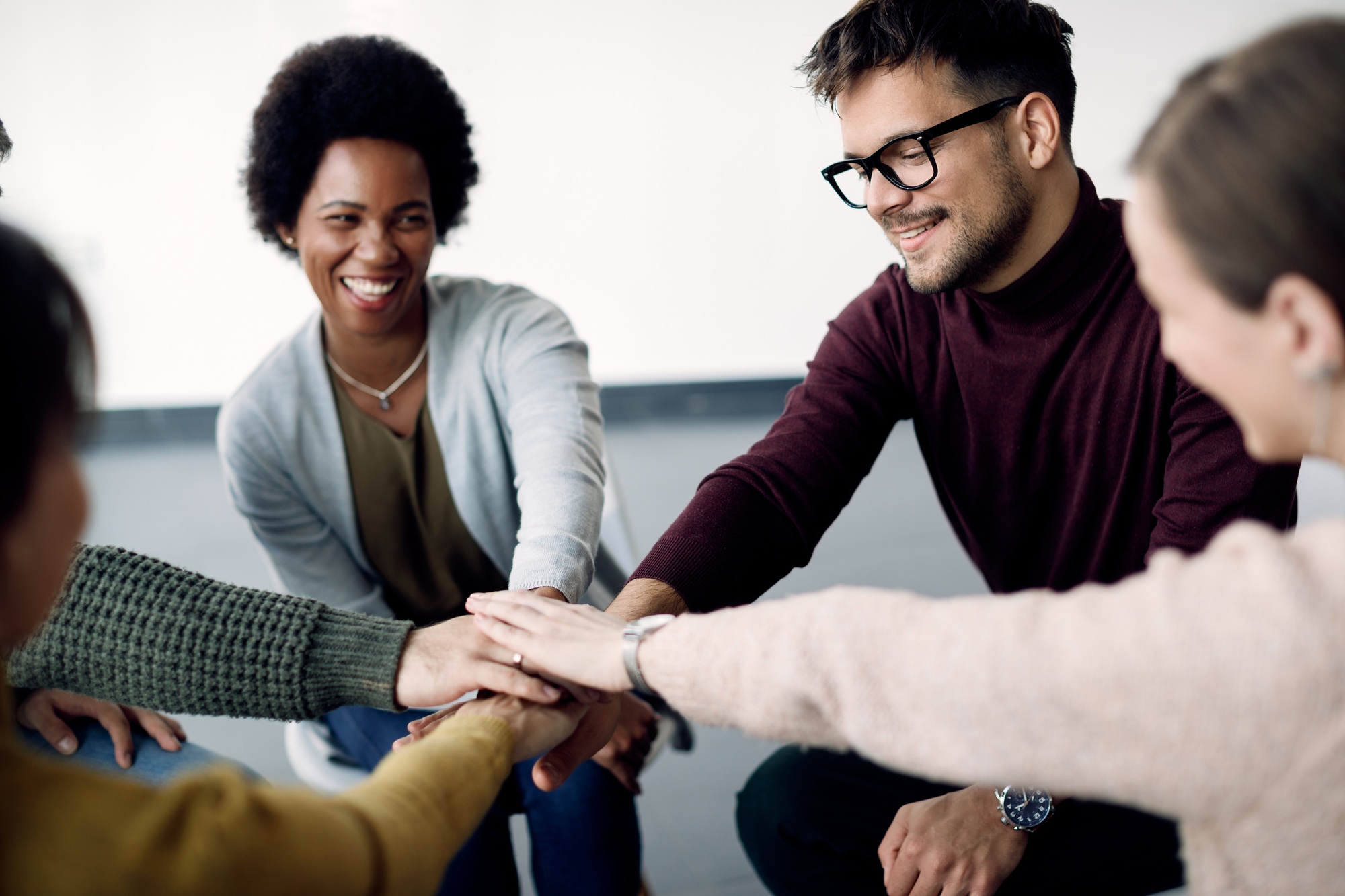 Attenders of group therapy joining hands in unity during a meeting.